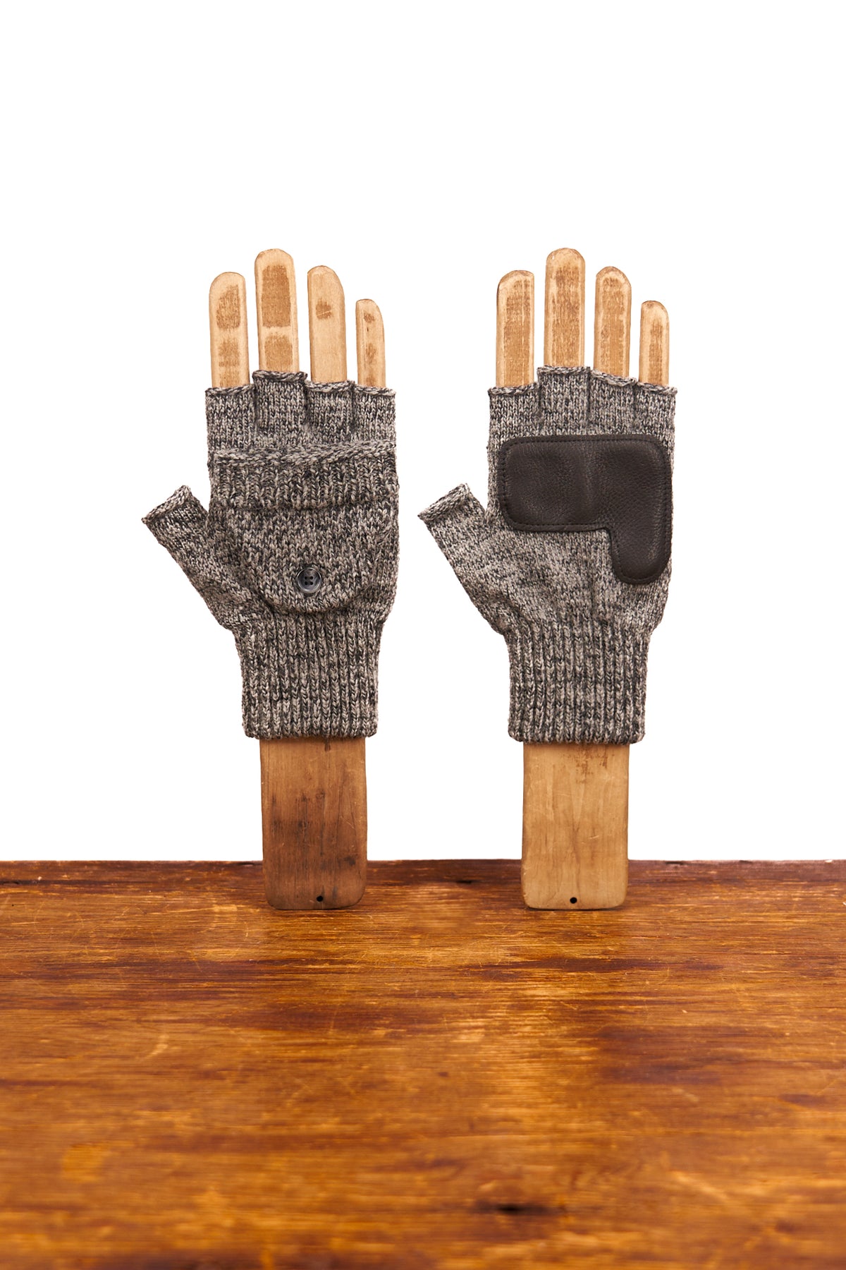 Pair of gray fingerless gloves on wooden sticks against a white background